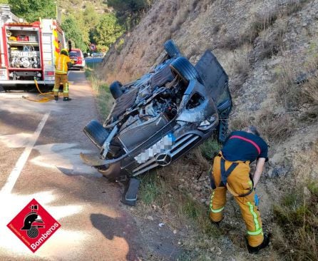 El coche volcado sobre la cuneta al poco de la llegada de los bomberos