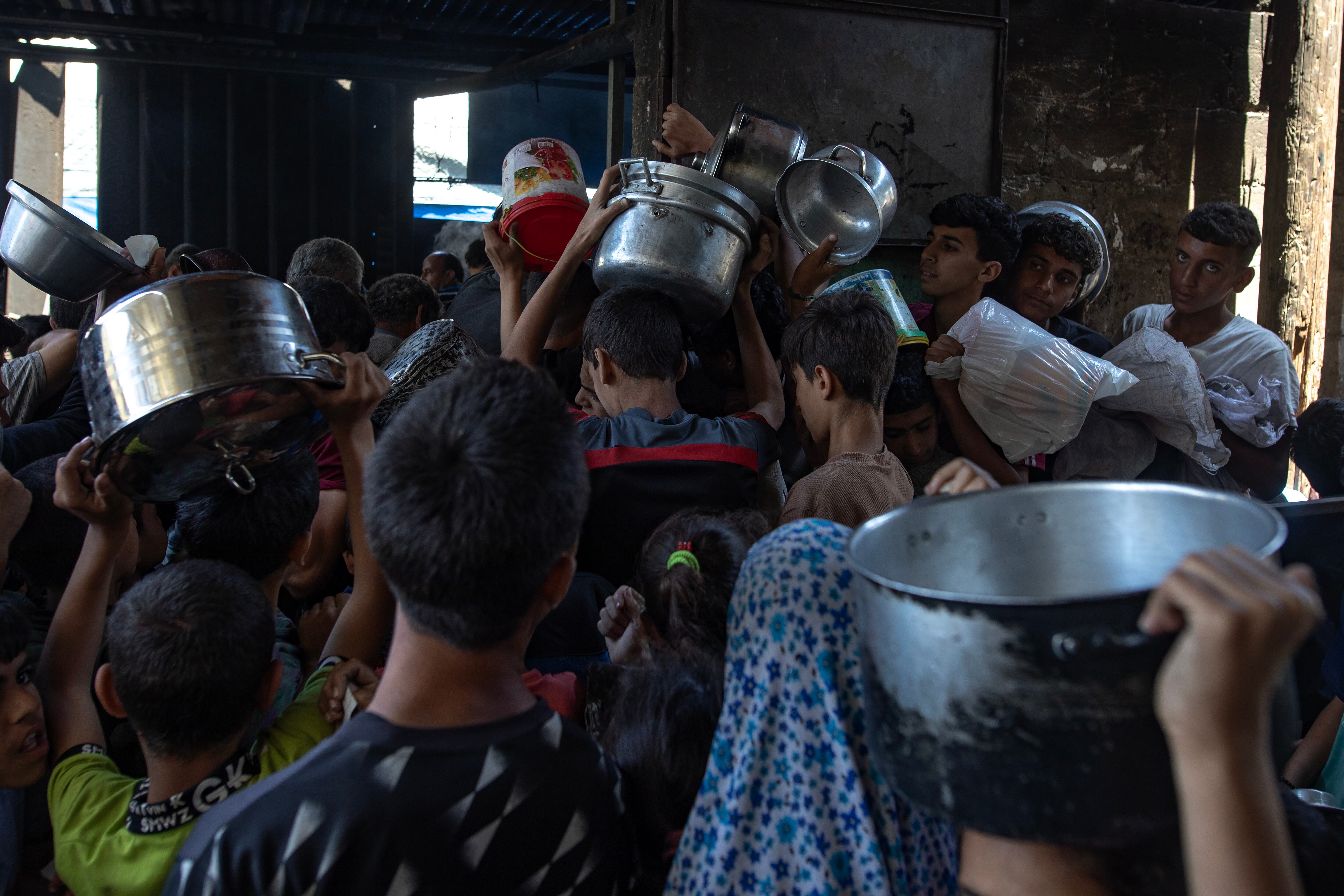 Cientos de palestinos se concentran con cacerolas y platos para tratar de conseguir comida en Gaza. EFE/EPA/HAITHAM IMAD