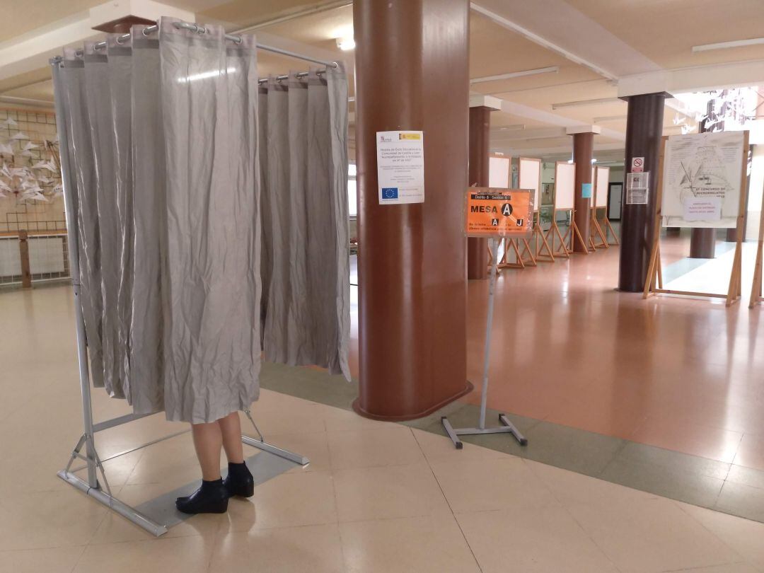 Una votante coge las papeletas antes de pasar por la urna