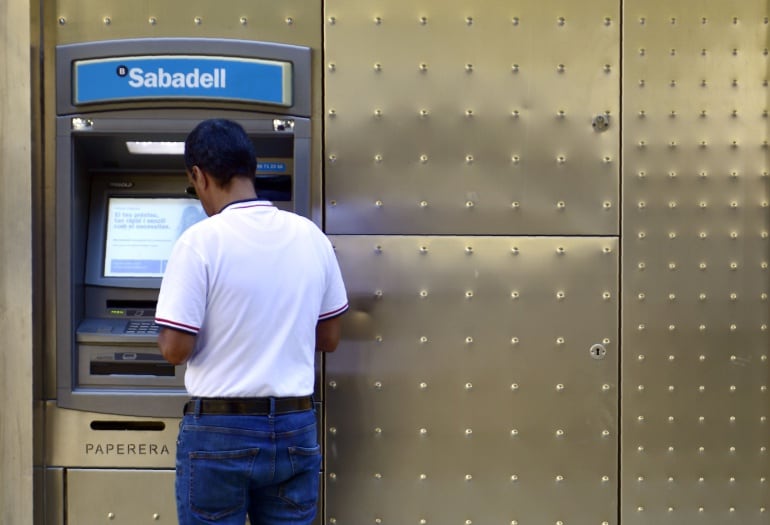 Un hombre frente a un cajero del Banco Sabadell