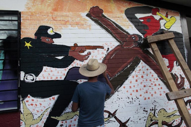 Un artista pinta un mural en la Escuela de Magisterio de Ayotzinapa, Guerrero, en la que estudiaban los jóvenes desaparecidos