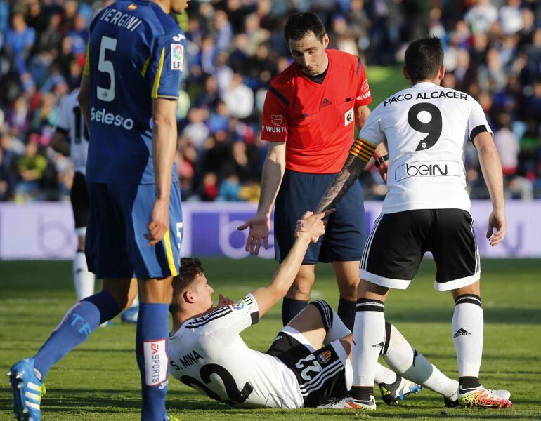 GRA463. GETAFE, 24042016.- El delantero del Valencia, Paco Alcacer (d), ayuda a su compañero, Santi Mina, ante el colegiado De Burgos Bengoetxea, durante el encuentro correspondiente a la jornada 35 de primera división, que han disputado esta noche frente