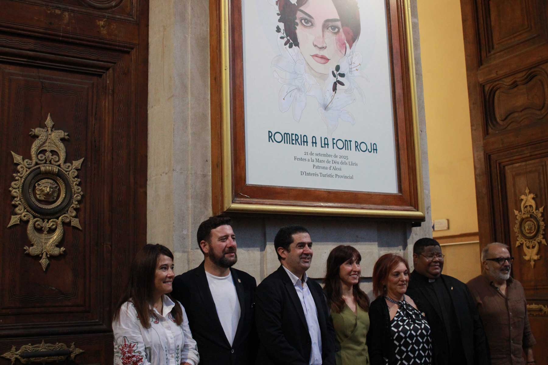 La autora, Lola Llopis, fotografiándose bajo su obra, con las autoridades presentes en el acto del descubrimiento del cartel