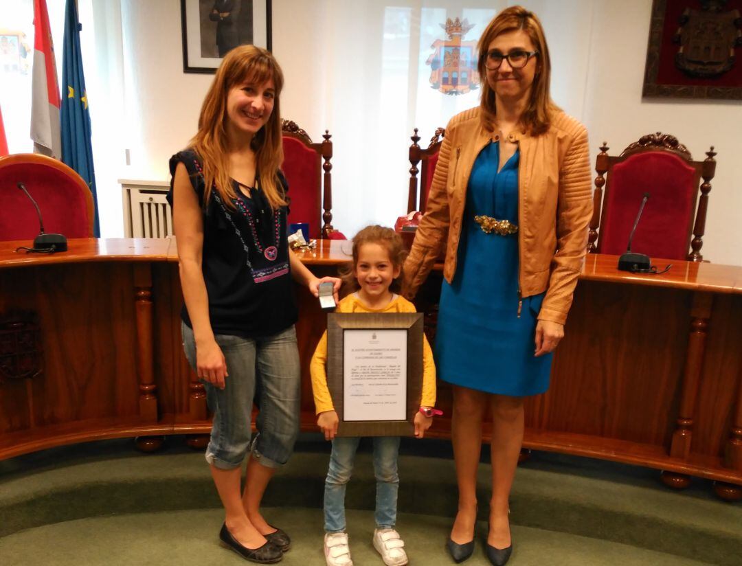 Irene muestra su diploma junto a su madre y a la alcaldesa