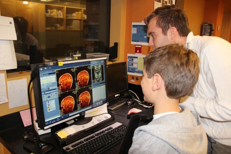 El investigador principal de este estudio muestra la resonancia magnética realizada al cerebro de un niño comparándola con la de un adulto. 