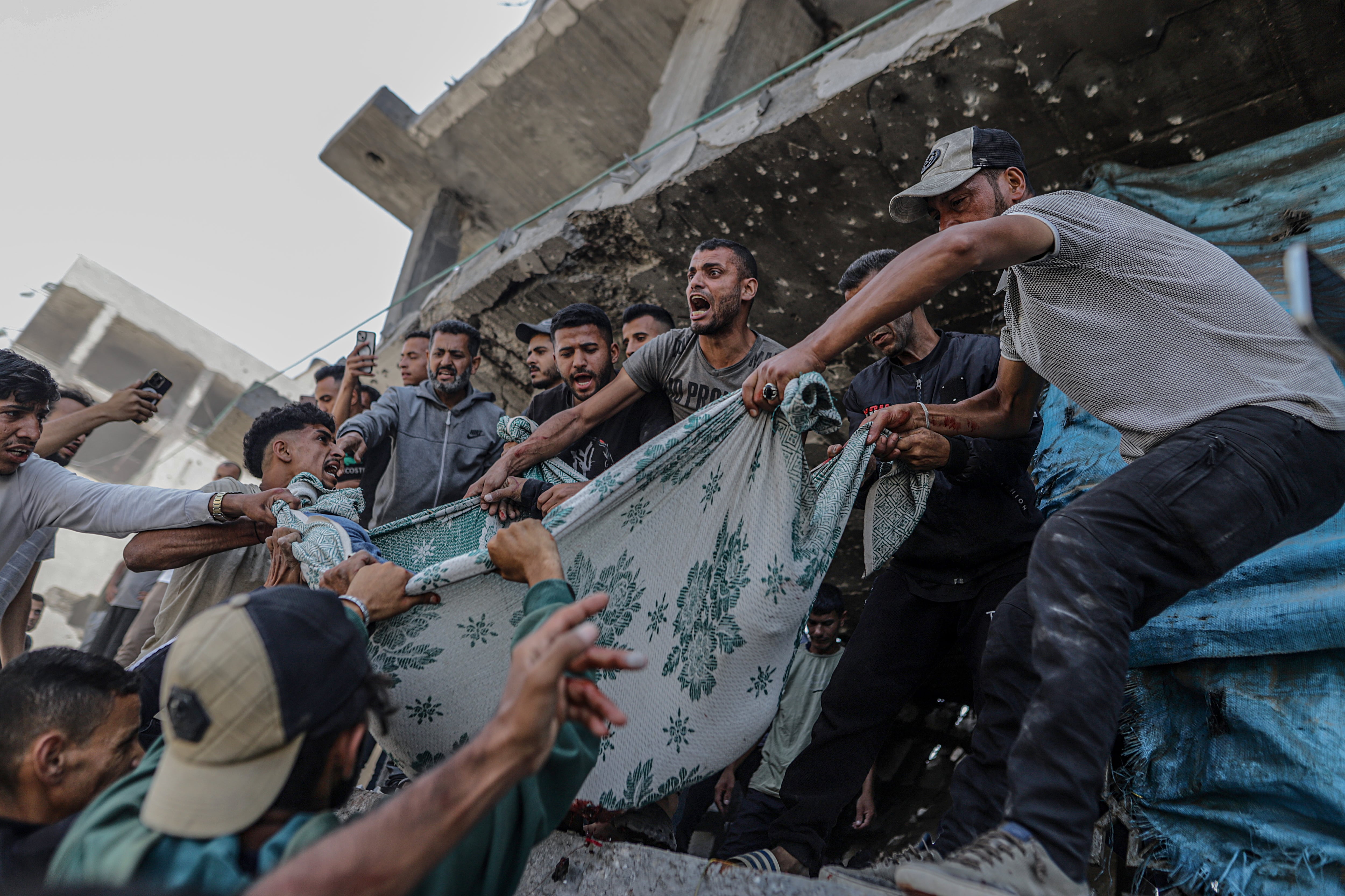 Palestinos desplazados recuperan un cuerpo de entre los escombros de un edificio destruido tras un ataque aéreo israelí en el barrio de Al Remal, en la ciudad de Gaza