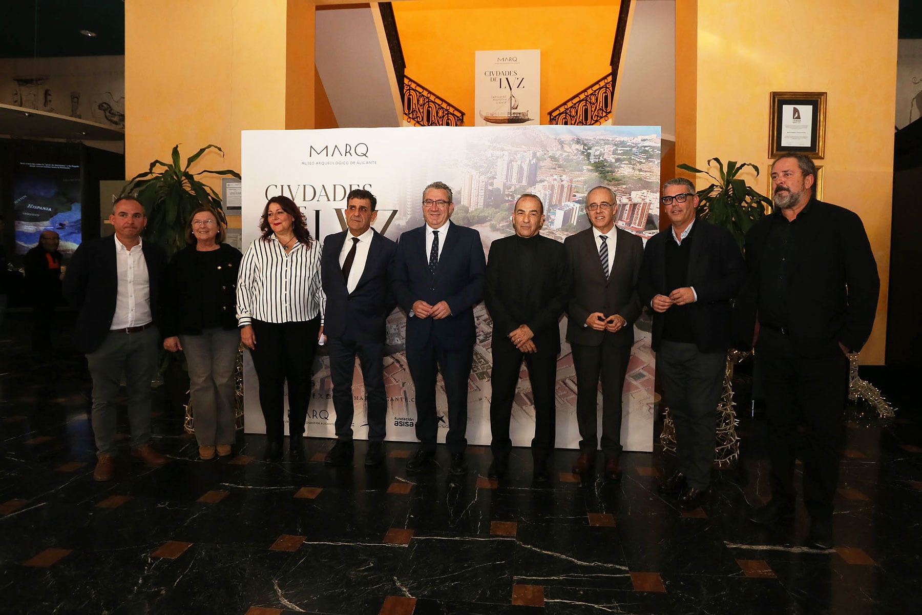 Las autoridades presentes en la inauguración posan ante el cartel anunciador de la nueva muestra del museo alicantino