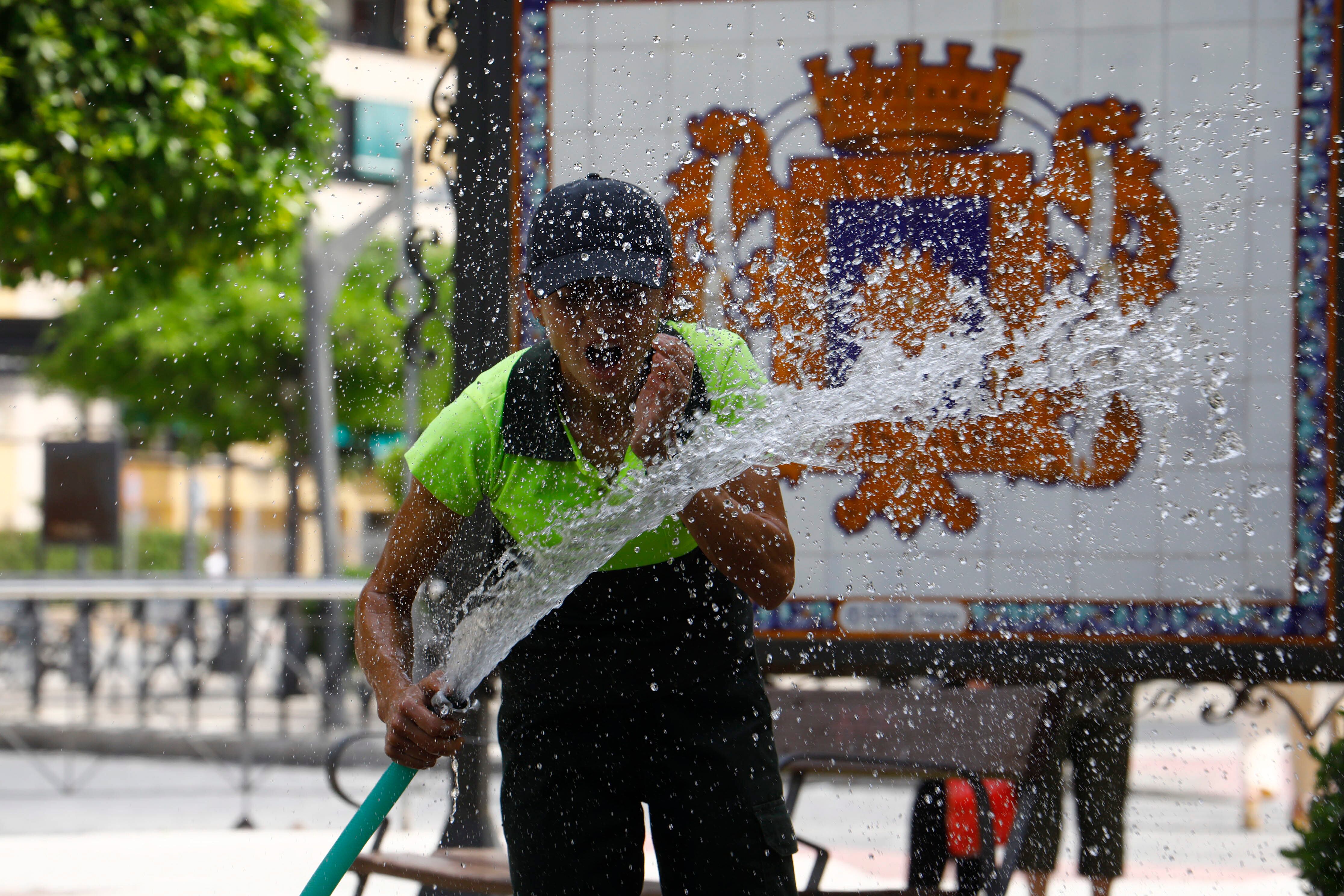 Una operaria se refresca con una manguera mientras realiza su jornada de trabajo, el pasado viernes en Écija (Sevilla).