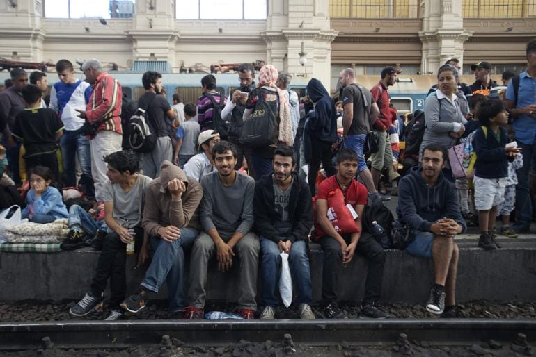 Refugiados esperan en un andén de una estación de trenes de Hungría.