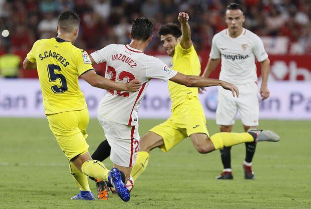 El centrocampista argentino del Sevilla, Franco Vázquez (2i), intenta llevarse el balón ante los jugadores del Villarreal, durante el encuentro correspondiente a la segunda jornada de primera división que disputan esta noche en el estadio Sánchez Pizjuán, en Sevilla.