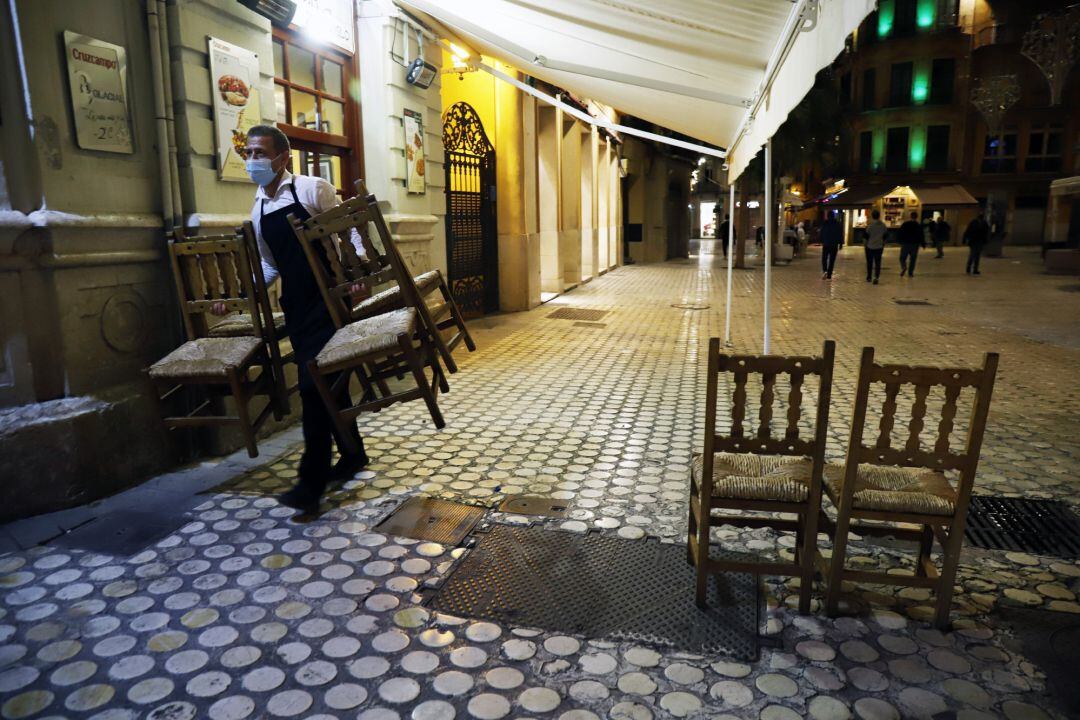 Un camarero se afanan en recogen la terraza del bar ubicado en el centro de la capital