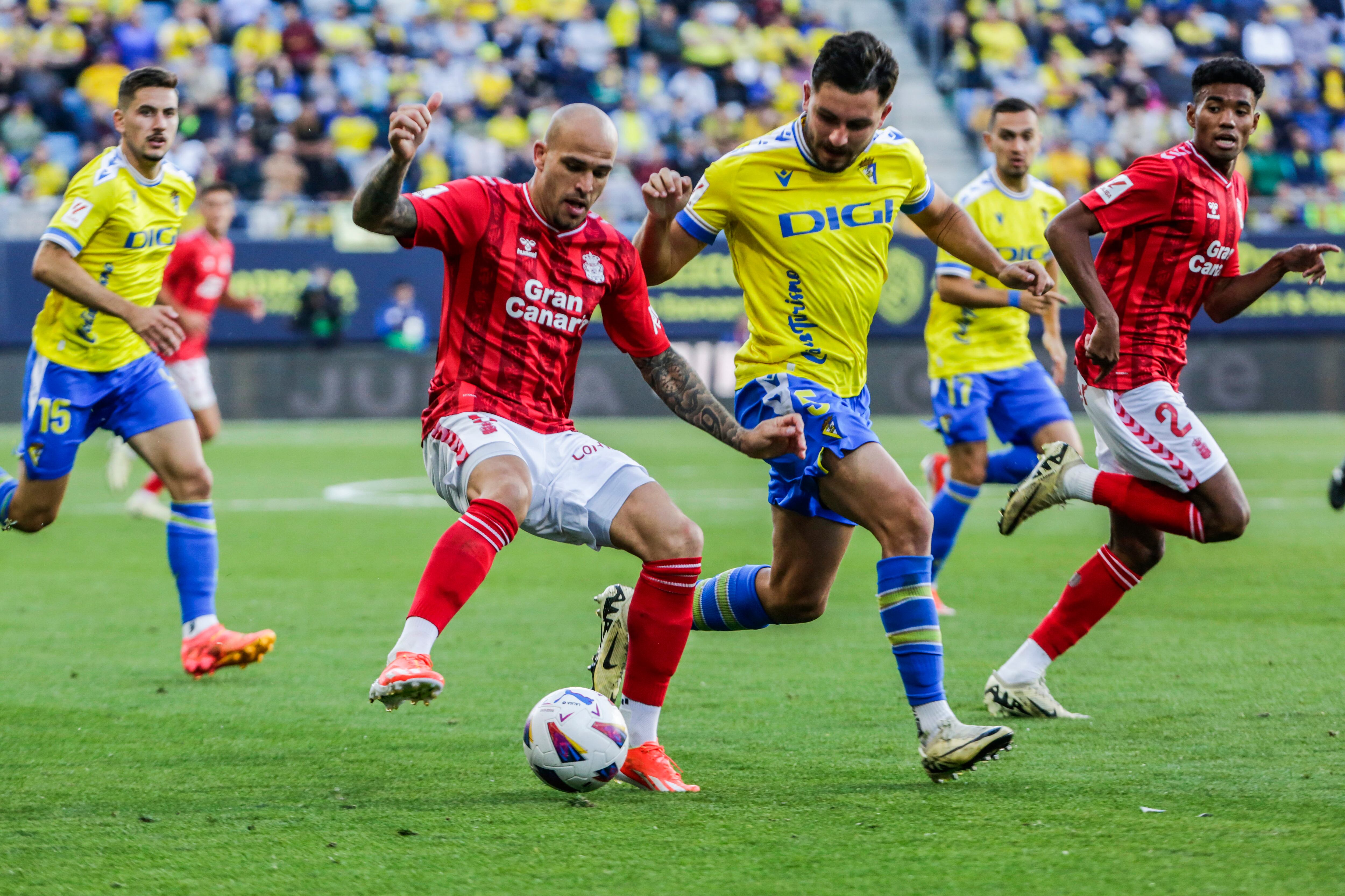 CÁDIZ, 19/05/2024.- El delantero de la UD Las Palmas, Sandro (i), con el balón ante el jugador del Cádiz, Víctor Chust, durante el encuentro correspondiente a la jornada 37 de Primera División que disputan hoy Domingo en el estadio Nuevo Mirandilla. EFE/Román Ríos.
