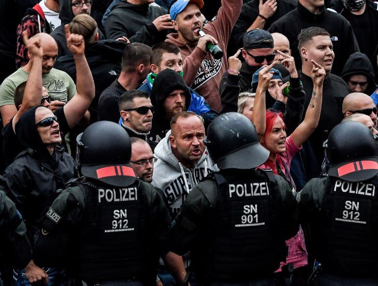 Manifestantes de derecha hacen gestos hacia la policía antidisturbios durante una manifestación en el lugar donde apuñalaron a un hombre.