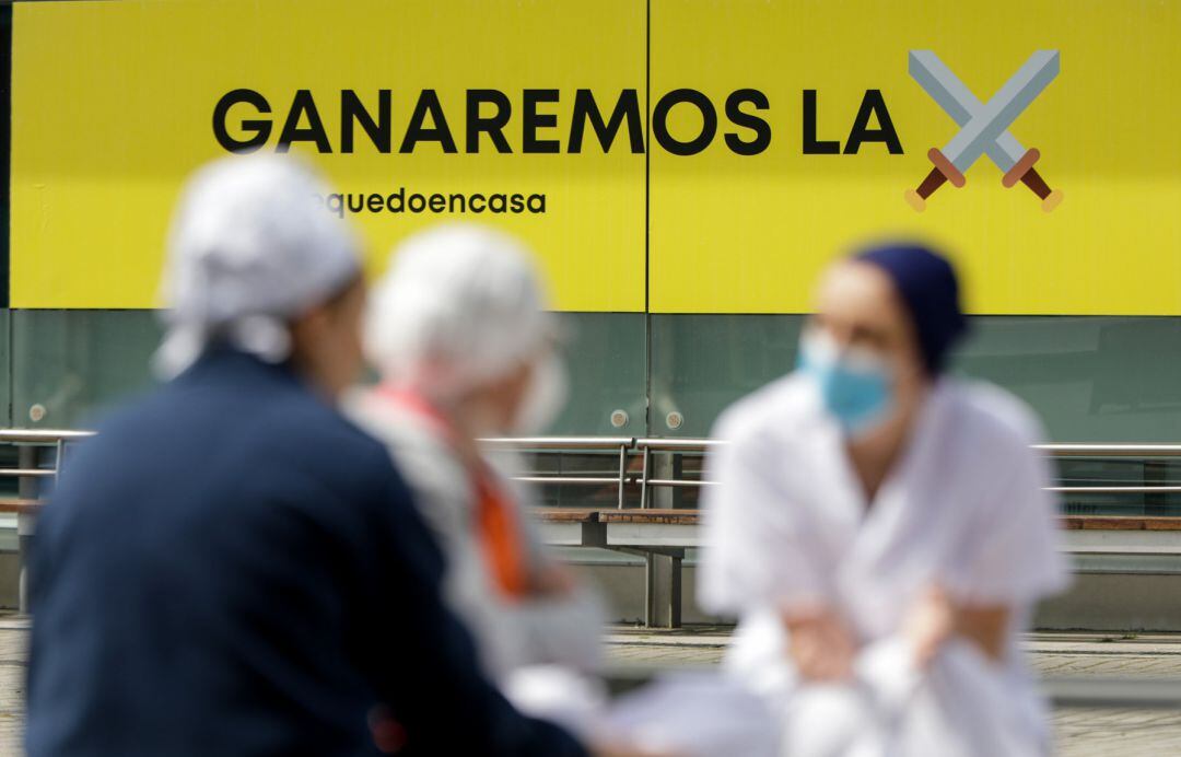 Sanitarios junto a un cartel en el que se lee 'Ganaremos la batalla' en el hospital de campaña de IFEMA.