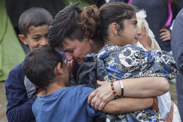 Una voluntaria de una ONG abrzada a varios niños mientras la policía continúa con el desalojo del campo de refugiados improvisado de la localidad de Polykastro, próxima a Idomeni (Grecia) hoy 13 de junio de 2016. La policía griega continuó hoy con la oper