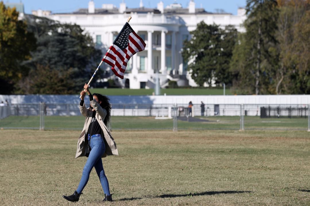 Una mujer, con la bandera de EEUU frente a la Casa Blanca tras las elecciones