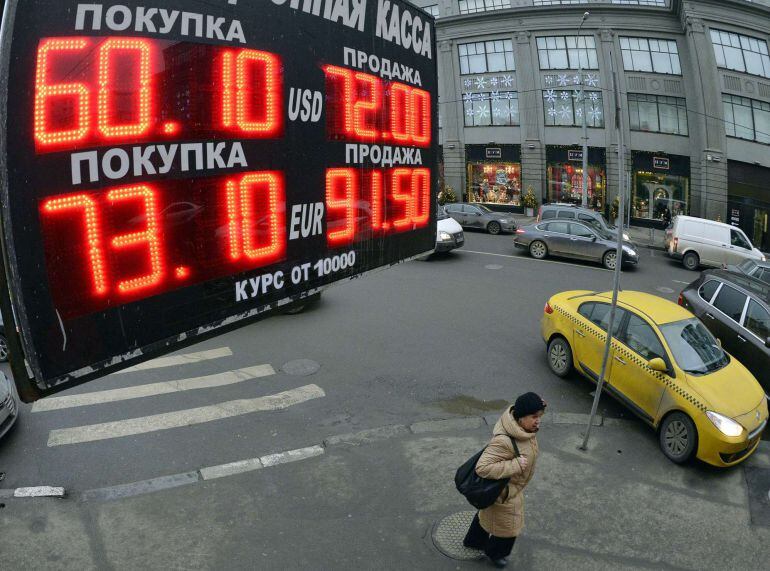 A woman walks under a board listing foreign currency rates against the Russian ruble outside an exchange office in central Moscow, on December 17, 2014. Russia scrambled on December 17, 2014 to halt a run on the ruble, selling billions of reserves to prop up the currency in the worst economic crisis of President Vladimir Putin&#039;s 15 years in power. AFP PHOTO / YURI KADOBNOV