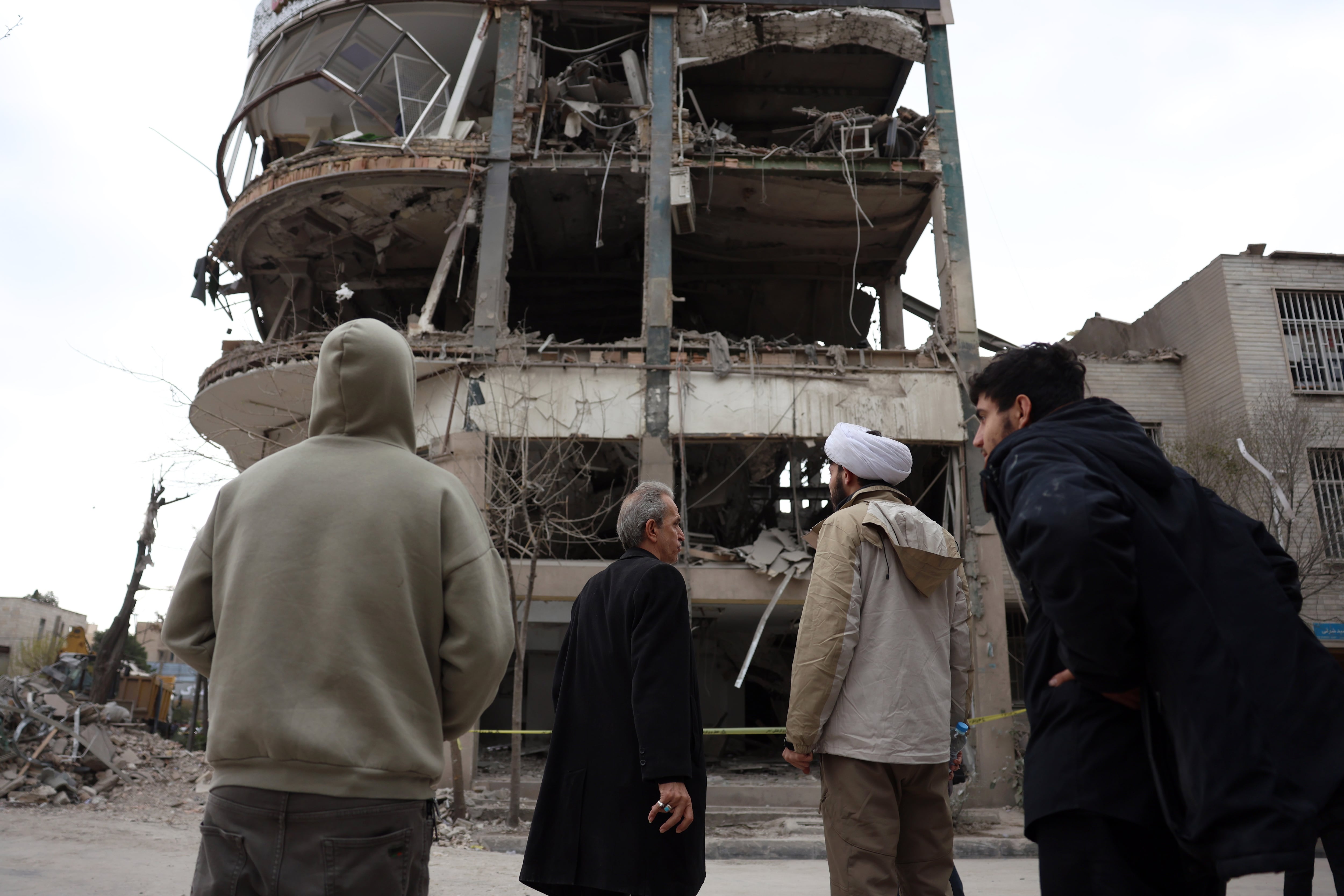 Varias personas observan los daños causados por un ataque sobre un edificio al norte de Teherán este domingo.