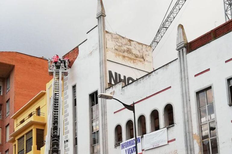 Los bomberos trabajan en la retirada de cascotes en la fachada del antiguo Cine Barrueco