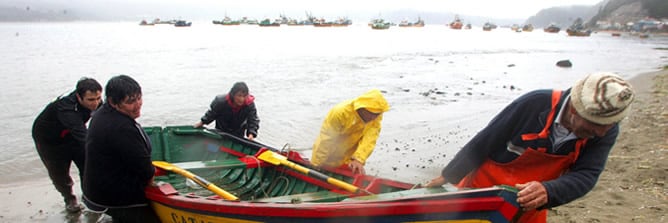 Pescadores retirando un bote de la costa en Dichato (Chile), este viernes