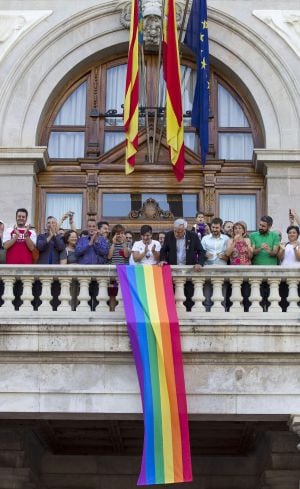 El alcalde de Valencia, Joan Ribó (centro), despliega, esta tarde, desde el balcón del Ayuntamiento la bandera arco iris con motivo del Día Internacional del Orgullo Lésbico, Gay, Transexual y Bisexual.