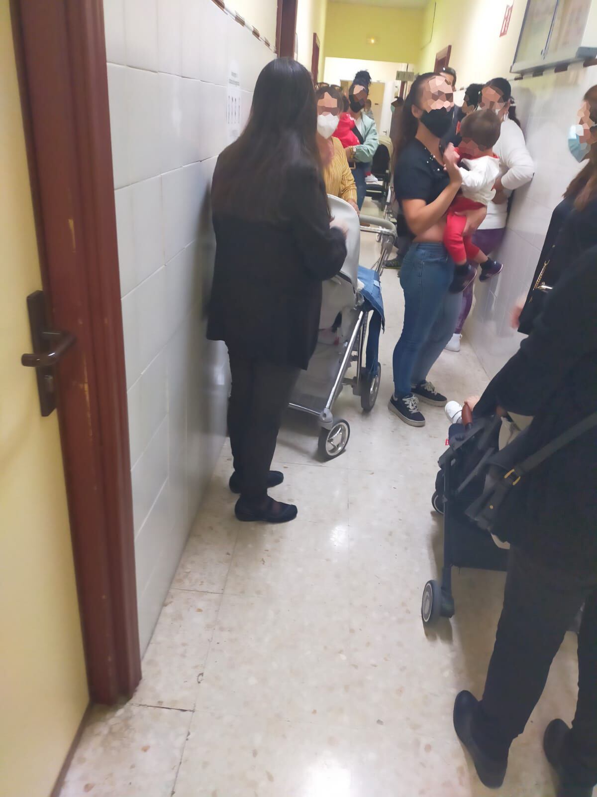 Padres, Madres y niños esperando en el pasillo su turno con el pediatra