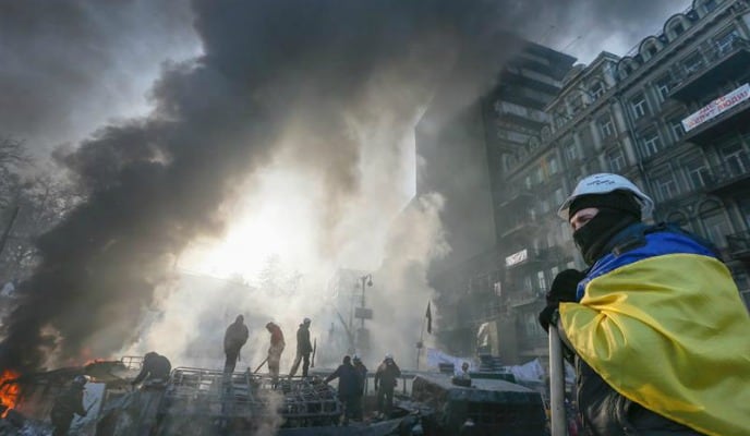 Imágen de un manifestantes antigobierno durante las protestas en Kiev, envuelto en la bandera ucraniana.