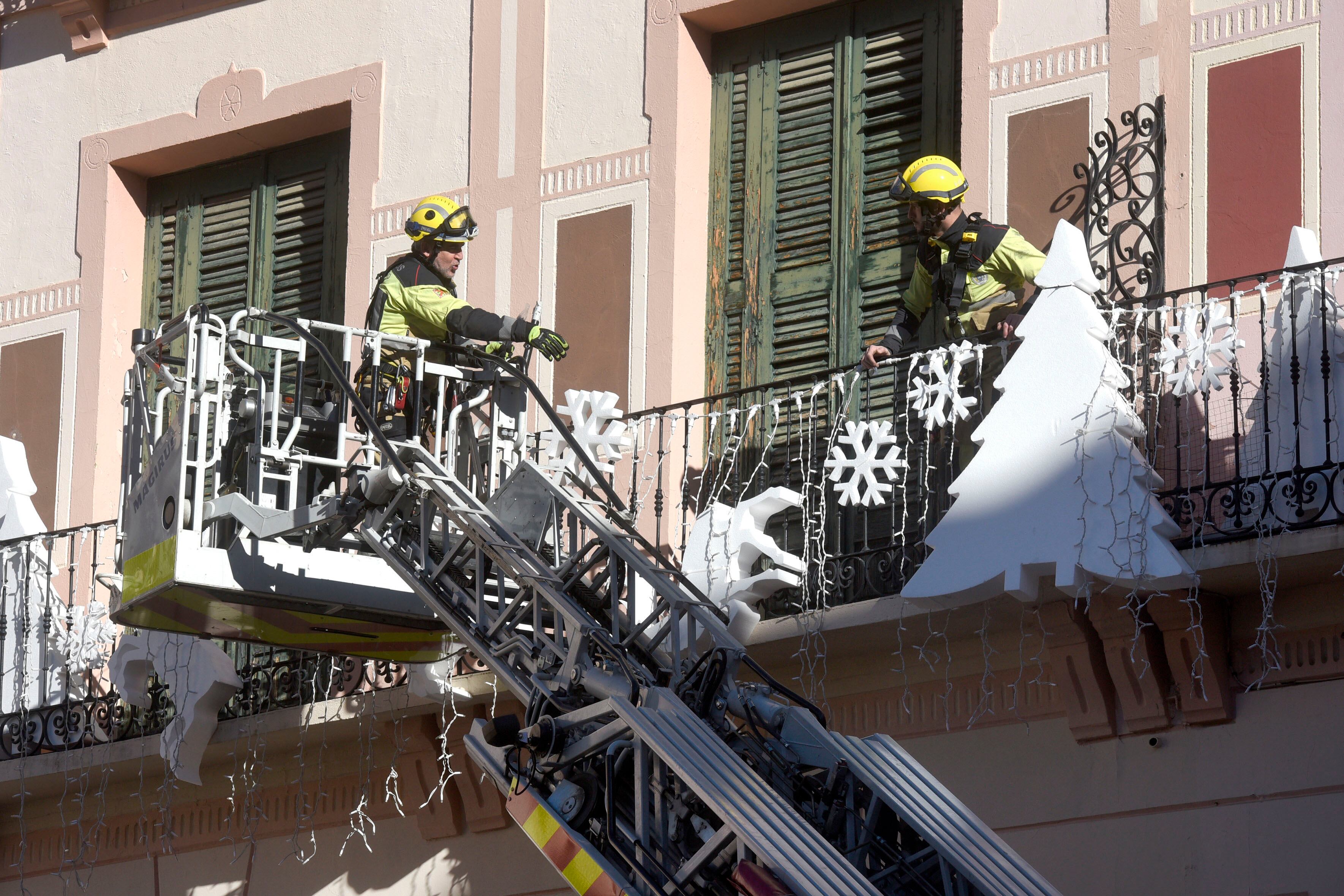 Bomberos aseguran los adornos de navidad de la Plaza López Allué, este sábado en Huesca. EFE/ Javier Blasco