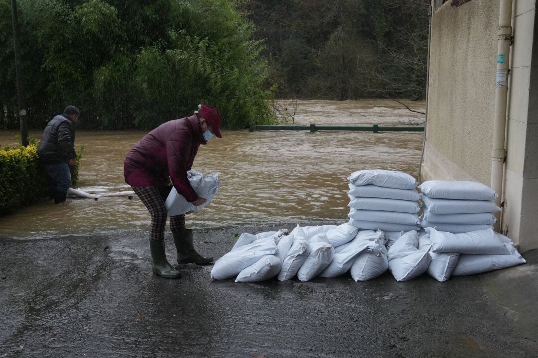 Varias personas colocan sacos para evitar la entrada de agua a un domicilio en Güeñes