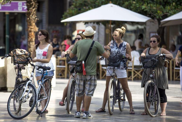 GRA036. VALENCIA, 21/08/2015.- Cuatro turistas que partricipan en un tour en bicicleta escuchan las indicaciones de su guía, este mediodía, en el centro histórico de Valencia. España recibió hasta julio un total de 37,9 millones de turistas extranjeros, lo que supone un 4,7 % más con respecto al mismo periodo del 2014, con lo que se consolida la senda del récord anual para el cierre del 2015. EFE/Manuel Bruque