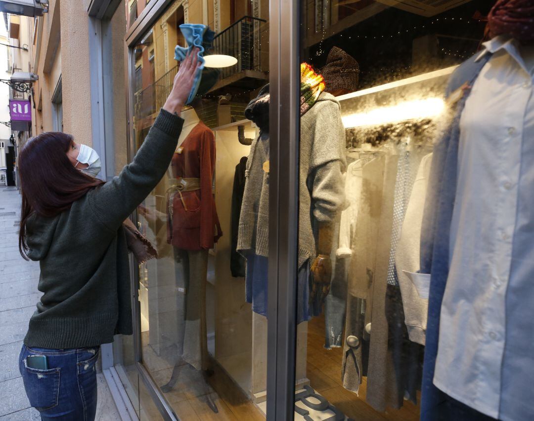 Una mujer limpia el escaparate de su tienda 