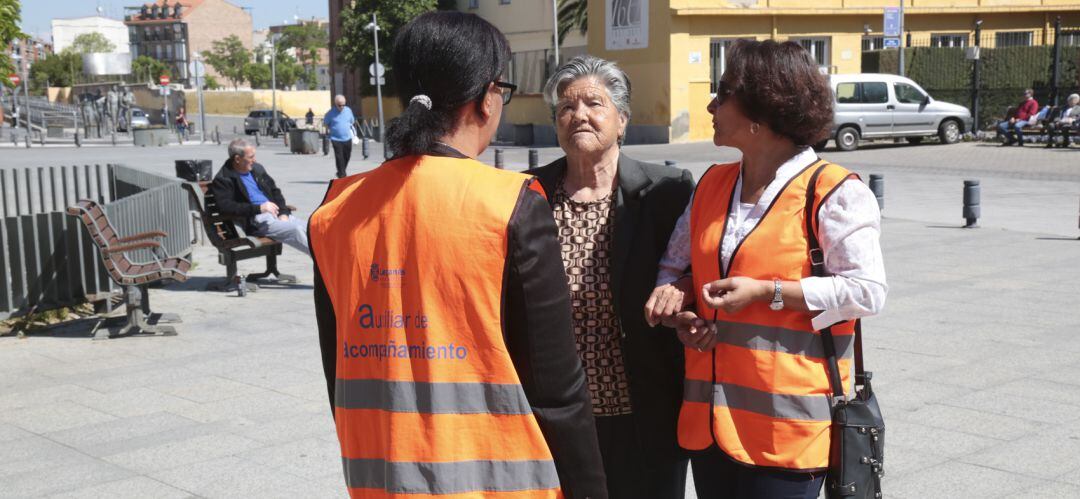 Dos de los auxiliares de acompañamiento junto a una persona mayor