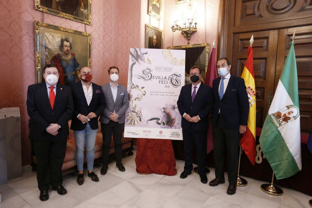 De izquierda a derecha, posando junto al cartel del &#039;Sevilla Fecit-21&#039;, José Roda, vicepresidente del Consejo de Cofradías; Francisco Carrera &#039;Paquili&#039;, presidente del Gremio de Arte Sacro; el pintor Rafael Laureano; Juan Carlos Cabrera, delegado municipa