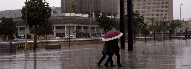 Una pareja se protege de la lluvia bajo un paraguas por el centro de Málaga, donde llovió el fin de semana del 20 de marzo.