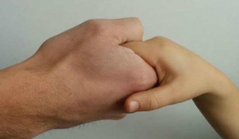 Un padre agarra la mano de su hijo