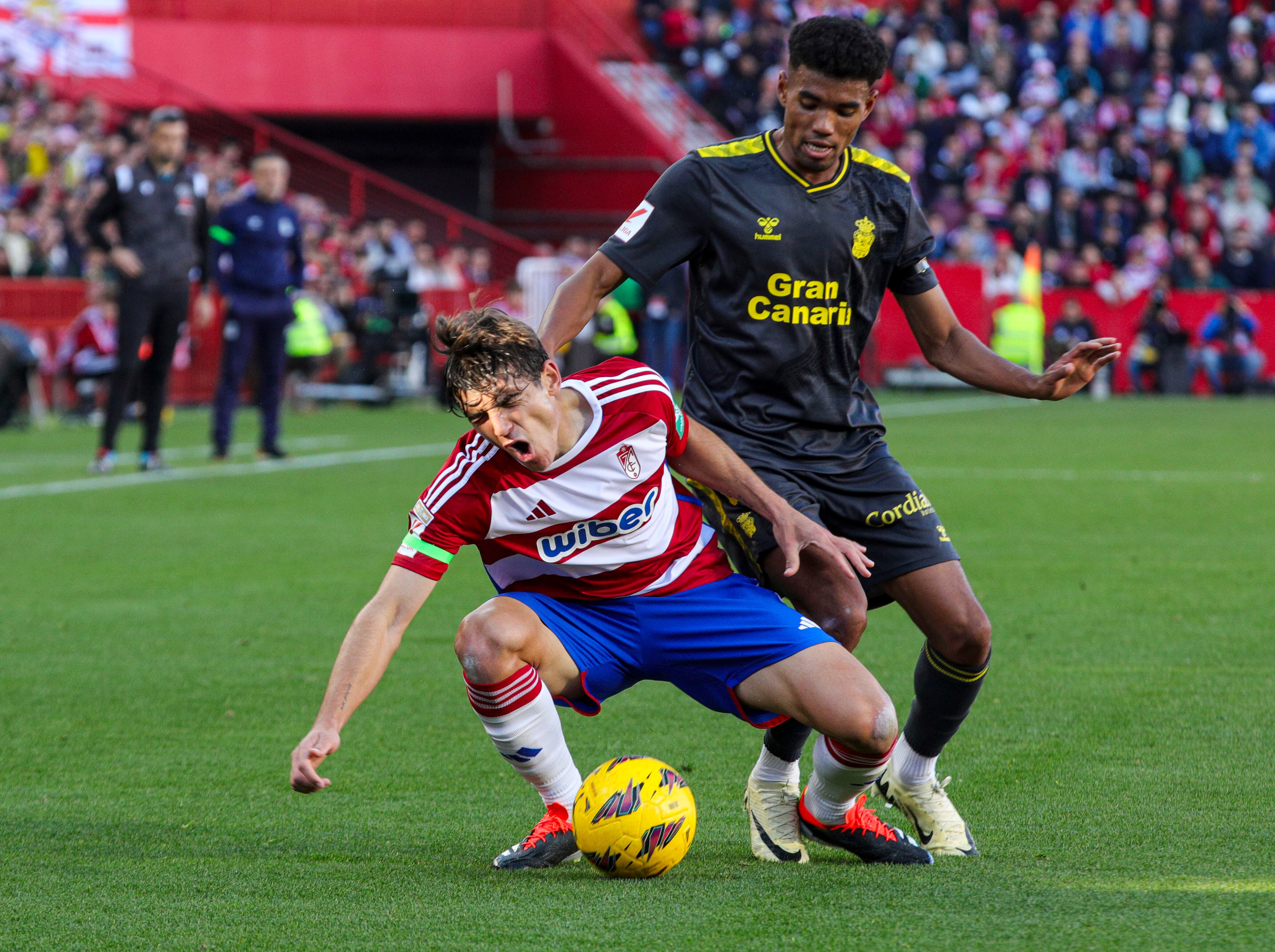 GRANADA, 03/02/2024.- El centrocampista del Granada Gonzalo Villar (i) cae ante el defensa de la UD Las Palmas, Marvin Olawale, durante el partido de LaLiga entre el Granada y la UD Las Palmas, este sábado en el Nuevo Estadio Los Cármenes. EFE/Pepe Torres.
