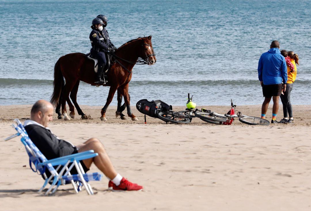 Una patrulla a caballo de la Policia Local de Valencia, vigila la playa de la Malvarrosa durante el primer fin de semana de cierre perimetral de las poblaciones de mas de 50.000 habitantes de la Comunidad Valenciana tras el repunte de casos de Covid-19