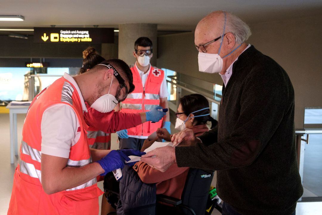 Personal de Cruz Roja toma la temperatura a los pasajeros procedentes de un vuelo de Madrid a su llegada al aeropuerto de Gran Canaria, 