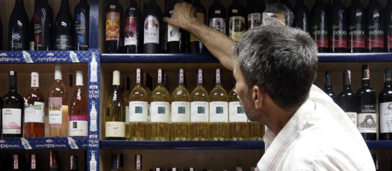 Un hombre elige una botella de una estantería.