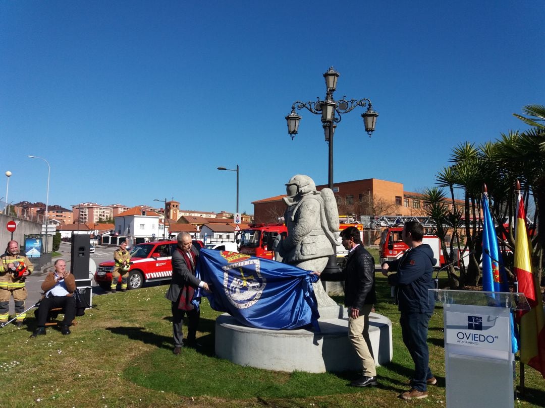 El alcalde de Oviedo, Wenceslao López descubre la escultura en memoria de Eloy Palacio. A la derecha el autor de la escultura y el hijo del bombero, David Palacio