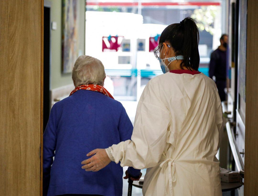 Una trabajadora de una residencia ayuda a una usuaria