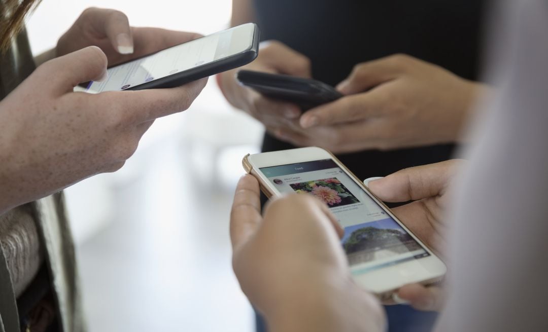 Un grupo de jóvenes interactúan con su teléfono móvil.