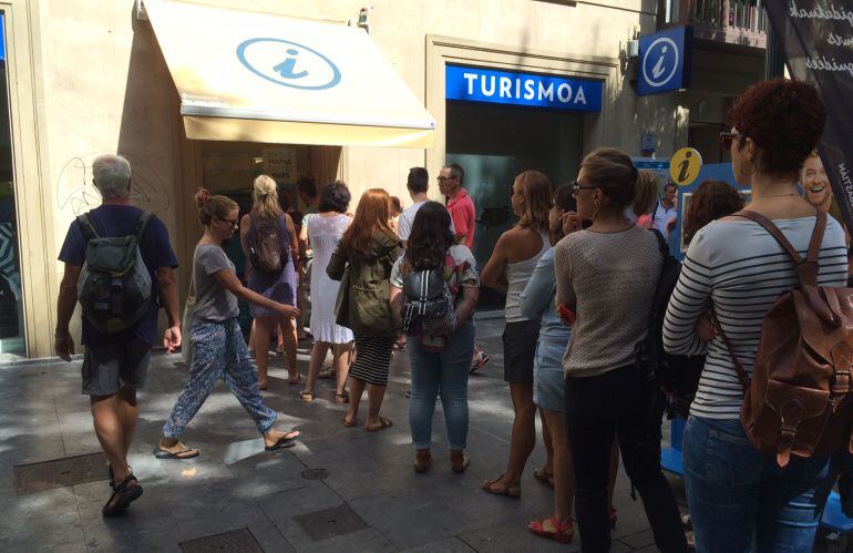 Varios turistas hacen cola para obtener un mapa de San Sebastián en la oficina de turismo.