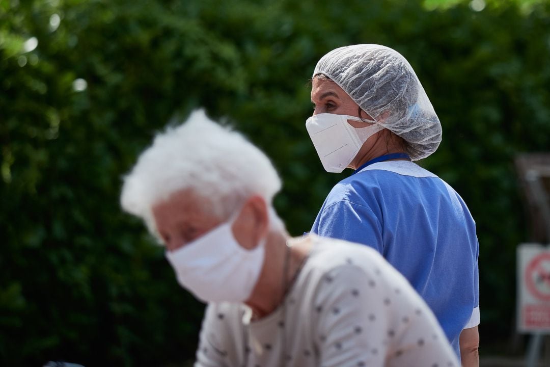 Una residente y una trabajadora sanitaria, ambas protegidas con mascarilla, de la ‘Casa de Misericordia’ en el exterior del centro donde han habilitado una zona de visitas