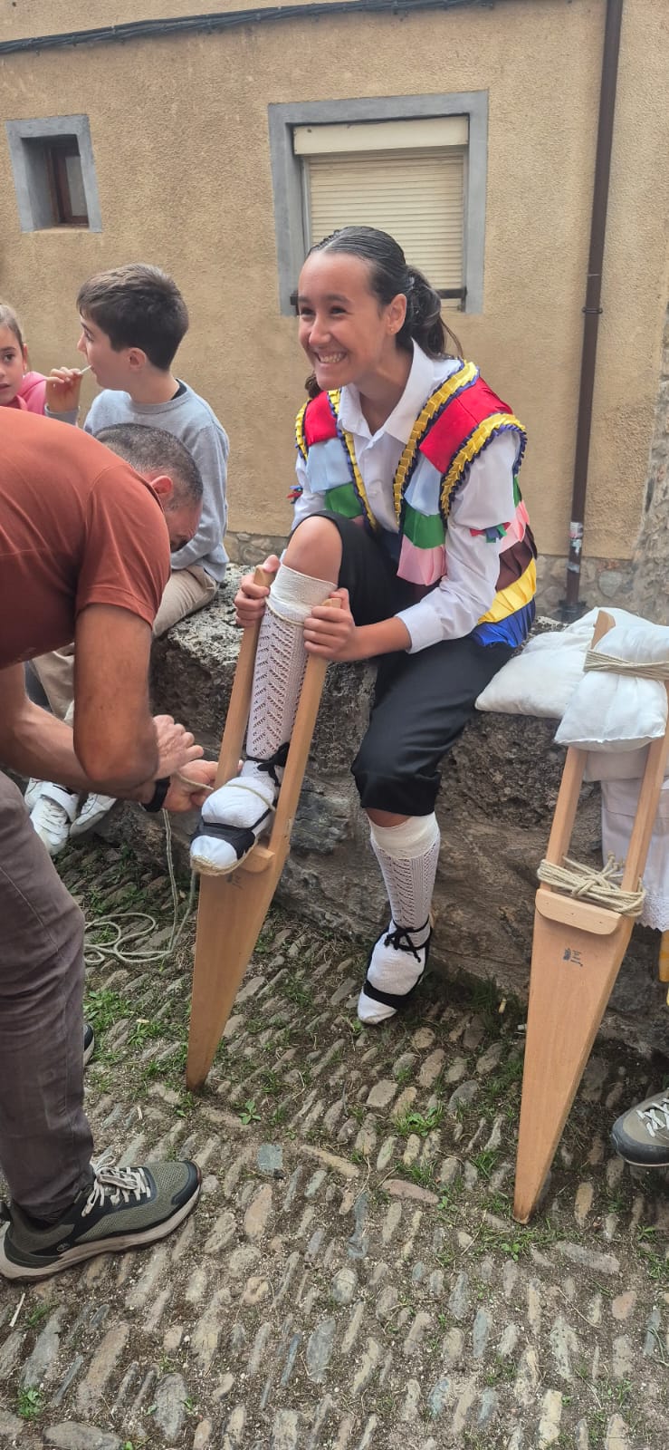 Adriana, ayudada por su padre para atarse los zancos antes de lanzarse por la cuesta de los danzadores en un día histórico en el folclore riojano.
