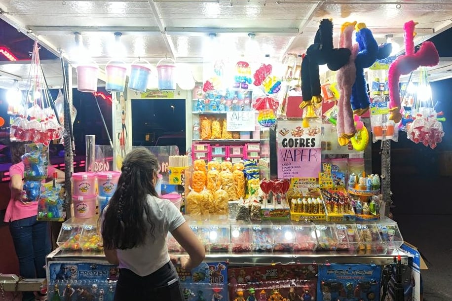 Una chica decide qué comprar en un kiosko de la feria de un barrio de Granada, en el que venden vapers.