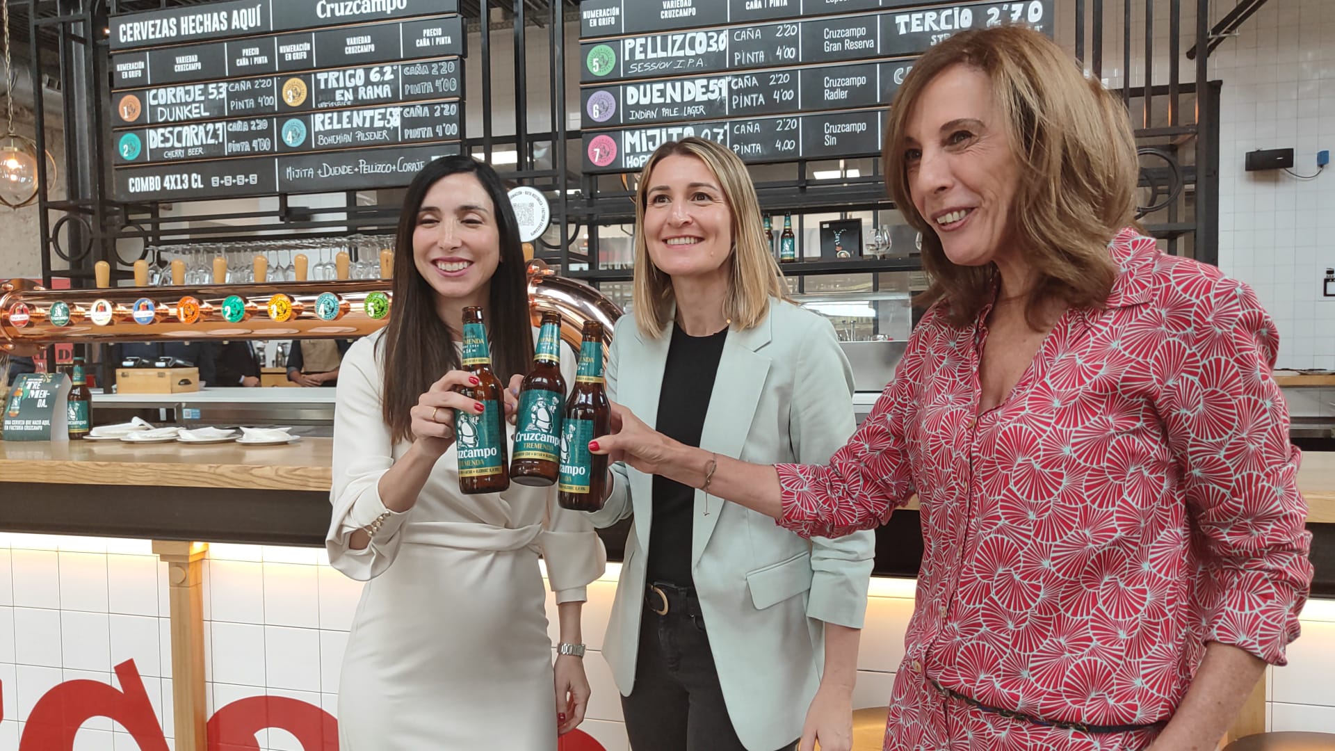 De izquierda a derecha, María Ruiz Sanguino, responsable de Cruzcampo; Elena Morales, directora de Innovación de Heineken España; y Regla Bejarano, directora de Fundación Cruzcampo, brindan con la nueva cerveza Tremenda