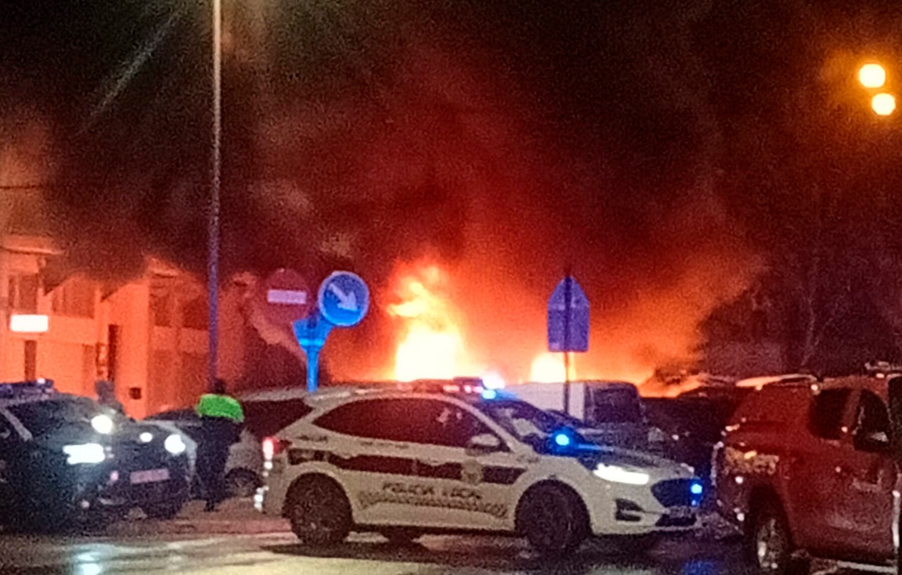 Imagen del incendio del vehículo tras el coche de la Policía Local