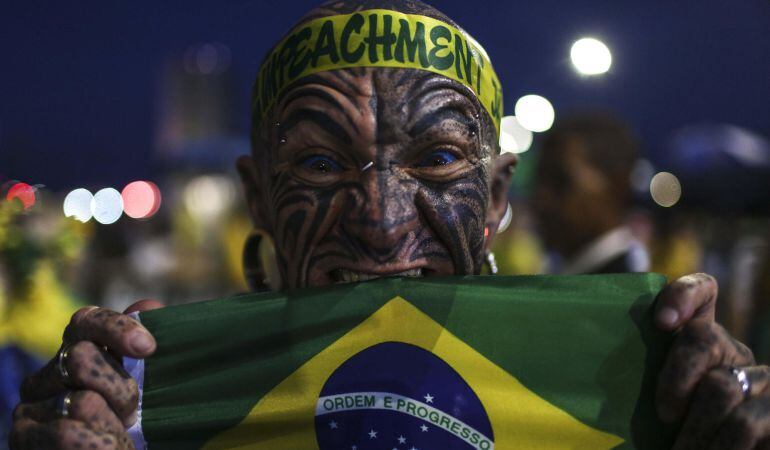 Un hombre muerde la bandera nacional de Brasil frente al Congreso Nacional durante una manifestación en contra del Gobierno.