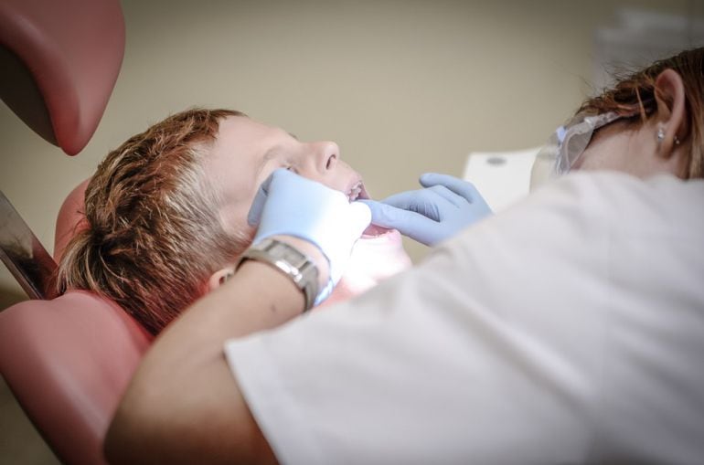 Imagen de archivo de un dentista examinando la boca de un niño. 